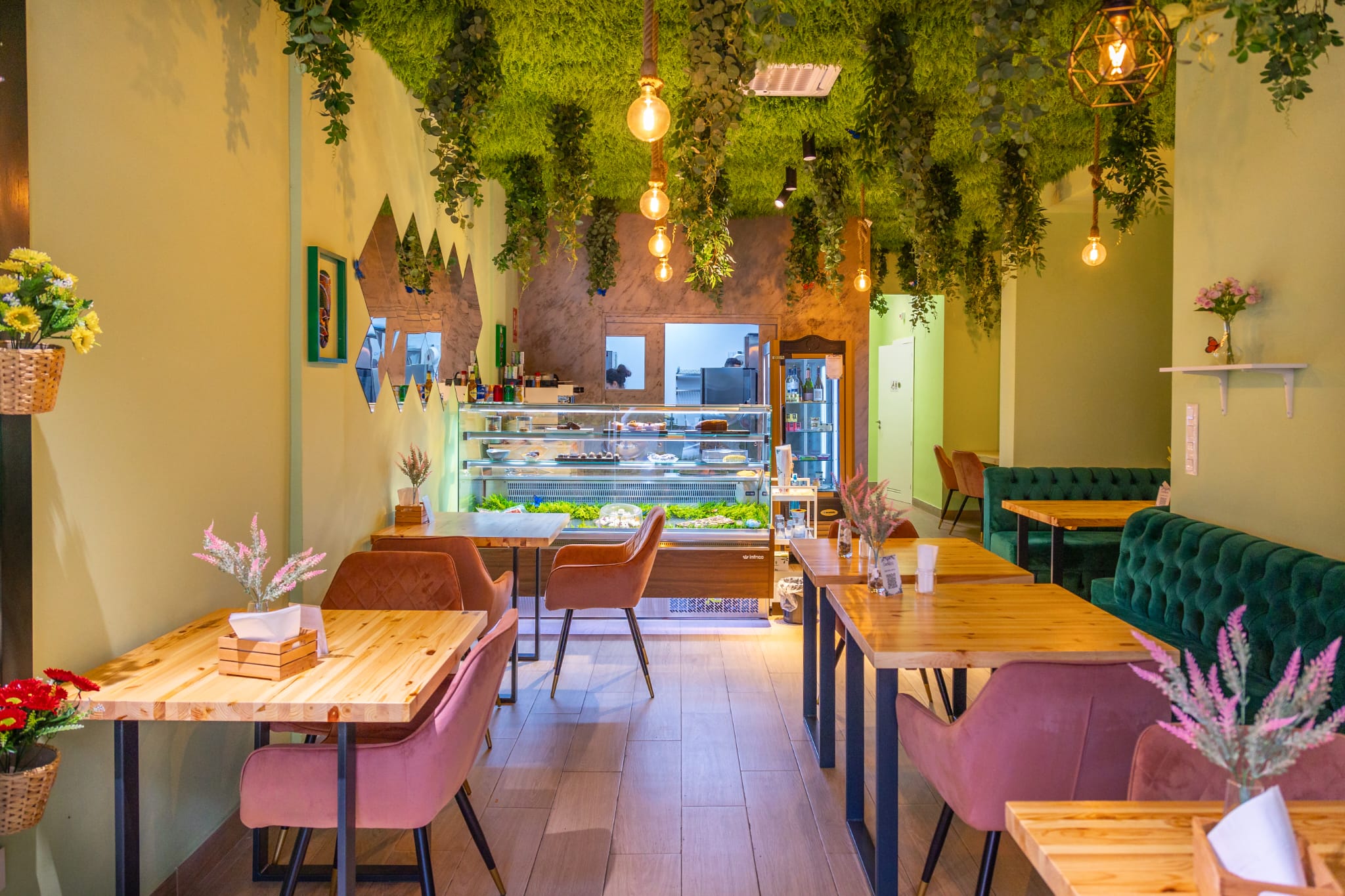 Interior del local de Cachitos con mesas, sillas rosas y plantas colgando